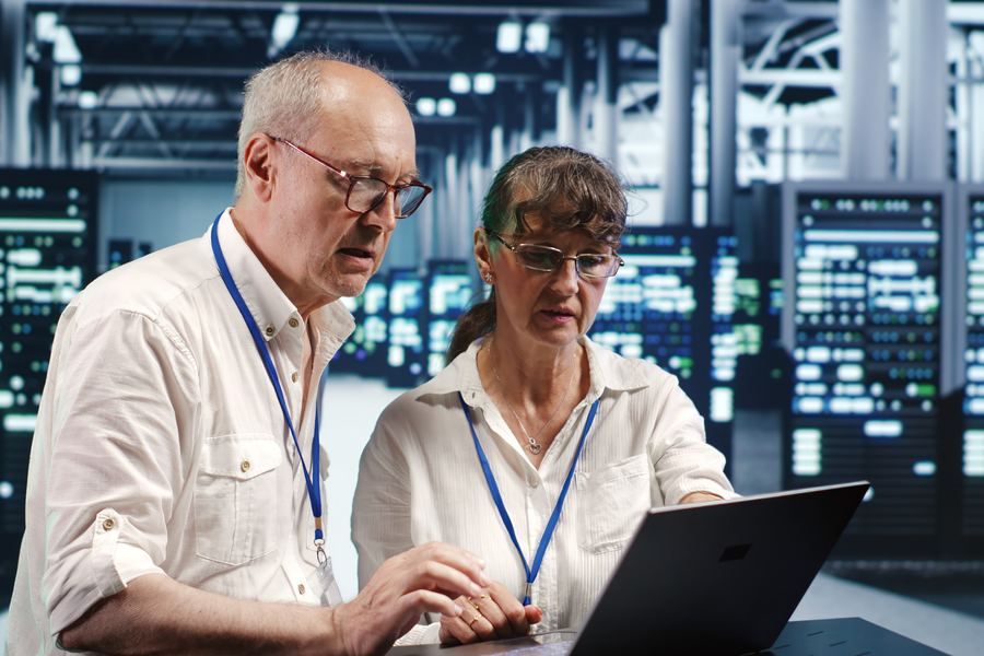 Two engineers reviewing privacy controls on a laptop in a server room