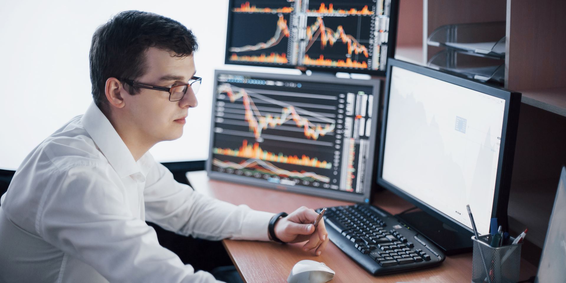Analyst reviewing automated decision-making outputs on several screens