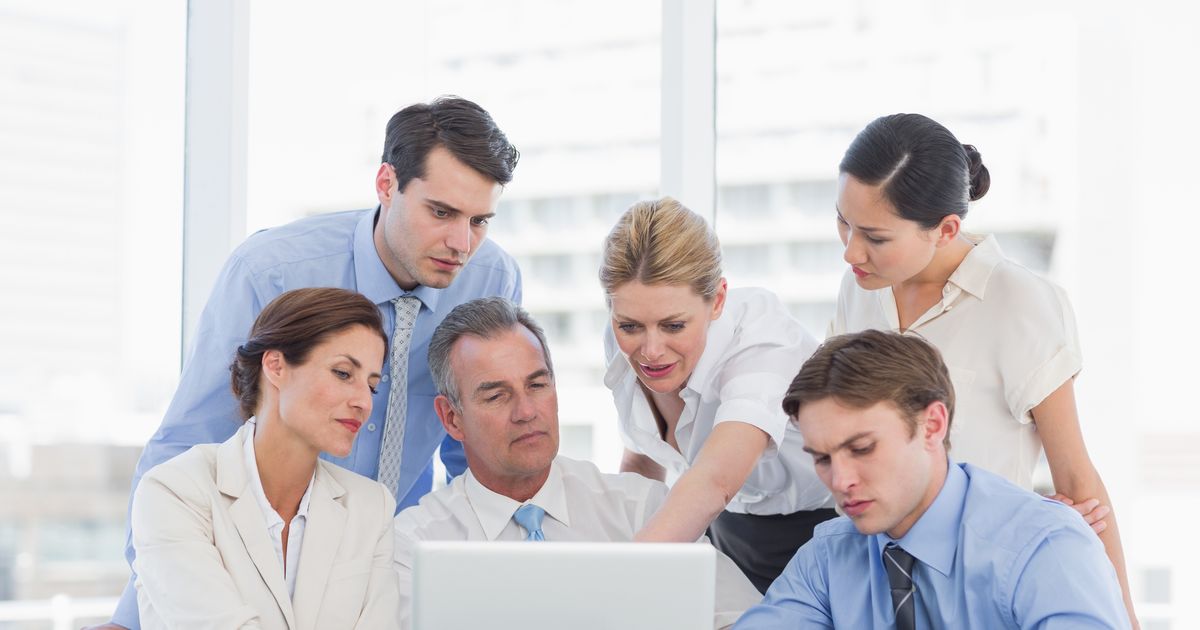 The Cybersecurity Executive Summary Every CEO and IT Manager Should See 5 Office team gathered around a laptop reviewing records, illustrating the PowerSchool data breach